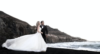 白天，新娘和新郎站在水体附近的岩层上